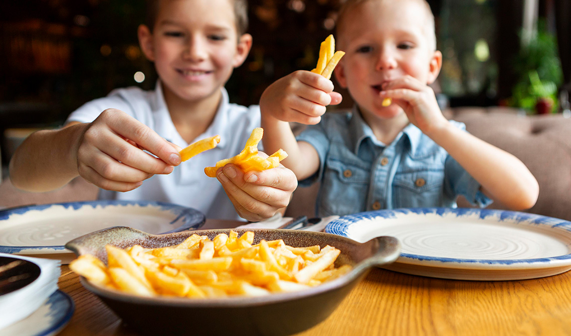 Niños felices comiendo patatas